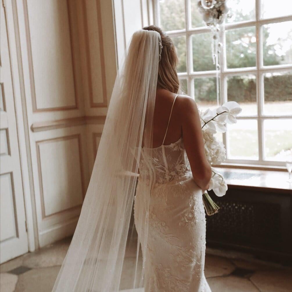 bride with veil off looking out window